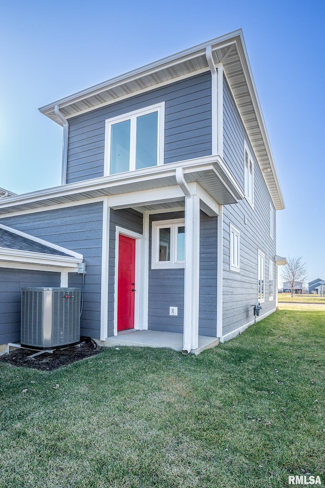 view of front of property with a front lawn and central air condition unit