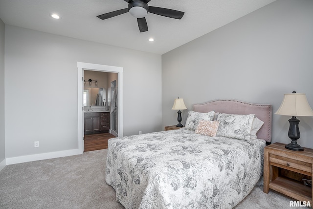 bedroom featuring ceiling fan, light carpet, and ensuite bath