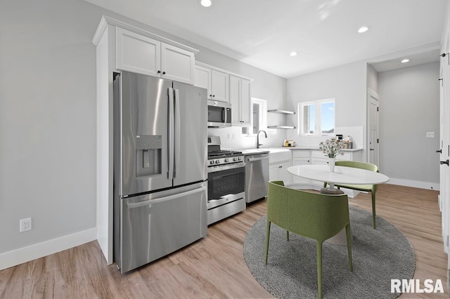 kitchen with white cabinets, stainless steel appliances, and light hardwood / wood-style flooring