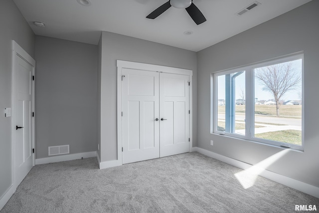 unfurnished bedroom with ceiling fan, a closet, and light carpet