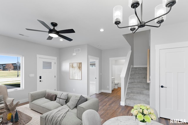 living room with dark hardwood / wood-style floors and ceiling fan with notable chandelier