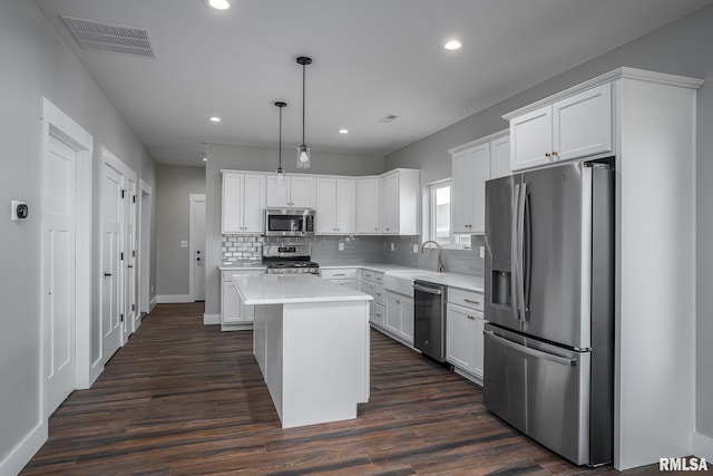 kitchen with stainless steel appliances, dark wood-type flooring, decorative light fixtures, a center island, and white cabinetry