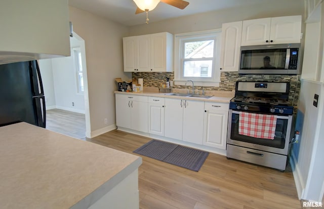 kitchen featuring white cabinets, sink, decorative backsplash, light wood-type flooring, and appliances with stainless steel finishes