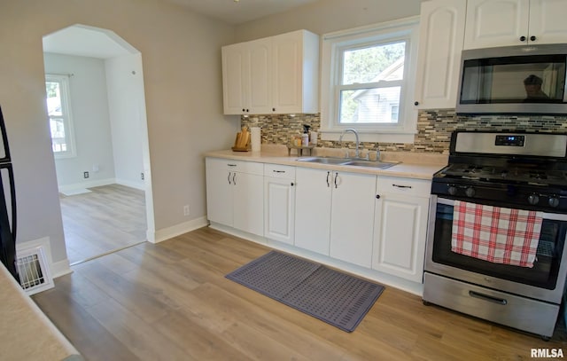 kitchen featuring sink, white cabinetry, stainless steel appliances, and a wealth of natural light