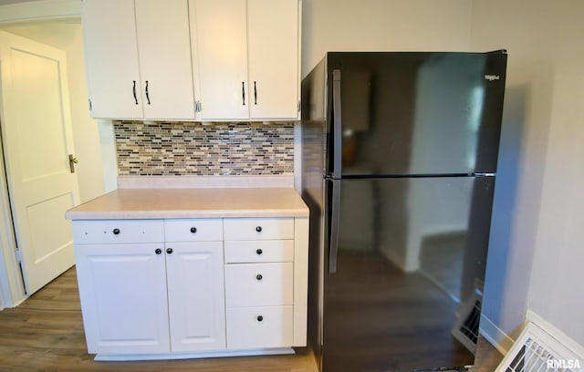 kitchen featuring backsplash, dark hardwood / wood-style flooring, white cabinetry, and black refrigerator