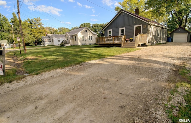 view of front facade featuring a garage, a front lawn, an outdoor structure, and a wooden deck