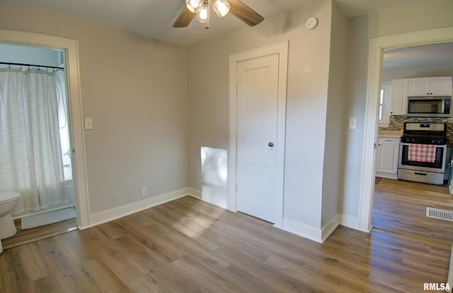 interior space with connected bathroom, light hardwood / wood-style flooring, and ceiling fan