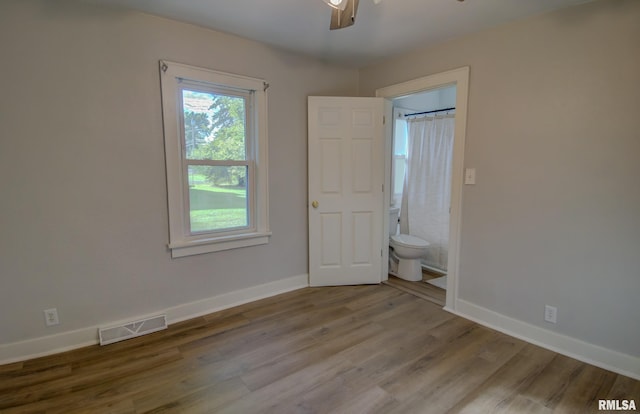 unfurnished bedroom with light wood-type flooring, ensuite bathroom, and ceiling fan