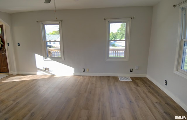 empty room with ceiling fan, light wood-type flooring, and a wealth of natural light