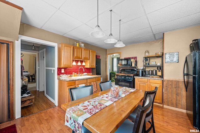 dining space featuring a drop ceiling, sink, and light hardwood / wood-style flooring