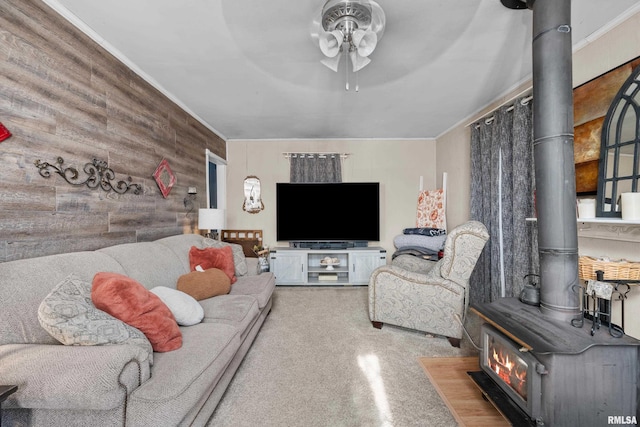 living room with ceiling fan, wood walls, and a wood stove