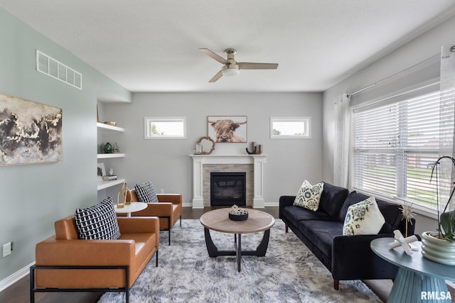 living room with built in shelves, hardwood / wood-style floors, ceiling fan, and a healthy amount of sunlight