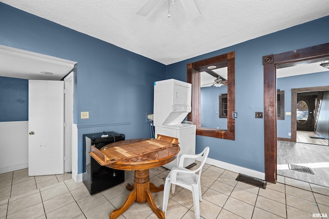 dining space with light tile patterned floors, stacked washing maching and dryer, and a textured ceiling