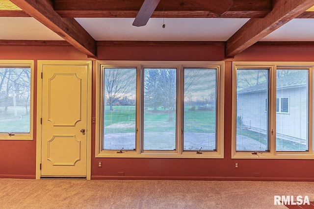 interior space featuring ceiling fan, beamed ceiling, and carpet flooring