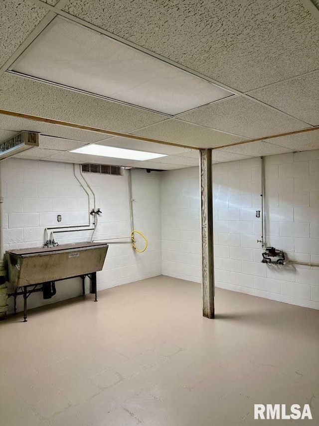 basement featuring a paneled ceiling and sink