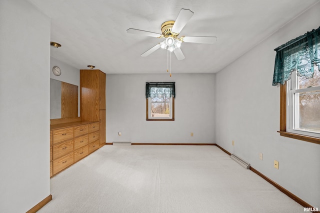 carpeted empty room featuring ceiling fan and a baseboard radiator