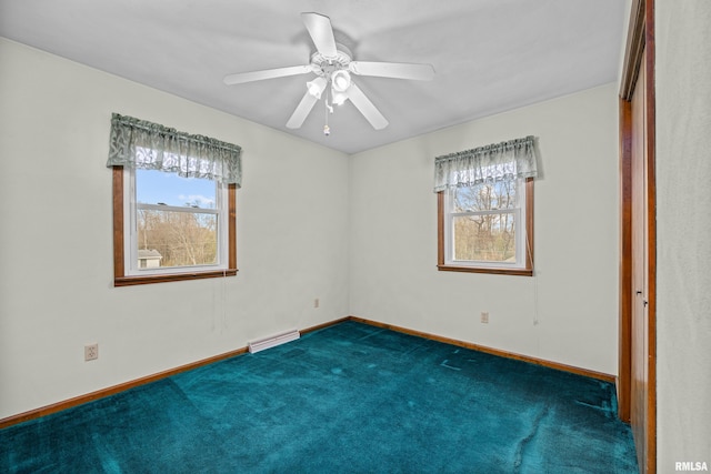 unfurnished room with dark colored carpet, ceiling fan, and a baseboard heating unit