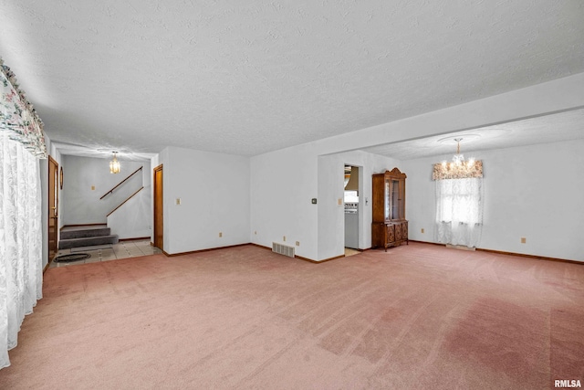 unfurnished living room with a notable chandelier, light colored carpet, and a textured ceiling