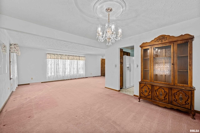 spare room with light carpet, a chandelier, and a textured ceiling