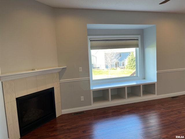 unfurnished living room featuring a fireplace, built in shelves, dark hardwood / wood-style floors, and ceiling fan