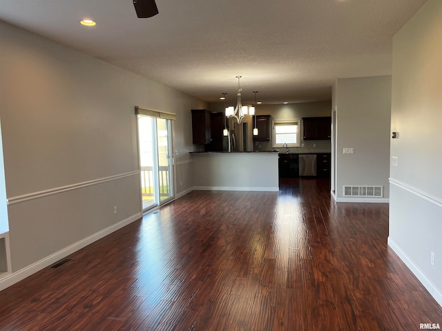 unfurnished living room with a chandelier and dark wood-type flooring