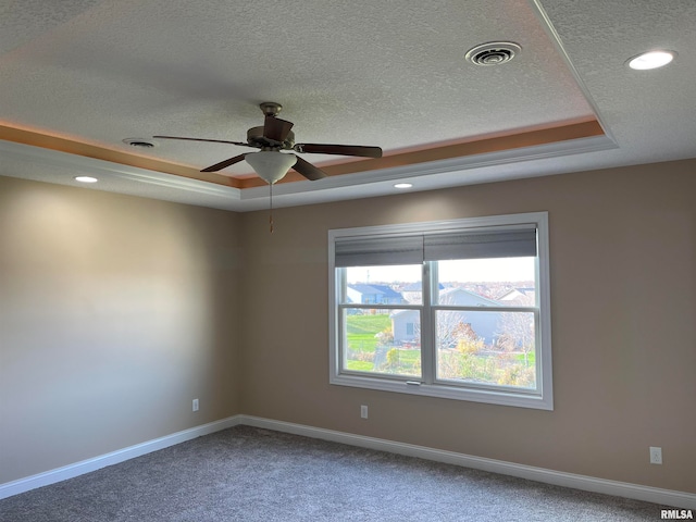 unfurnished room with a textured ceiling, carpet floors, a raised ceiling, and ceiling fan