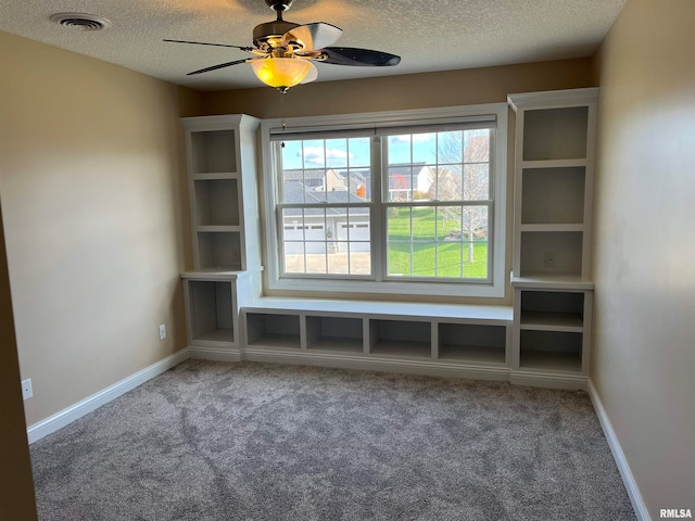 carpeted spare room featuring ceiling fan and a textured ceiling