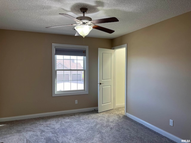 spare room with a textured ceiling, light colored carpet, and ceiling fan