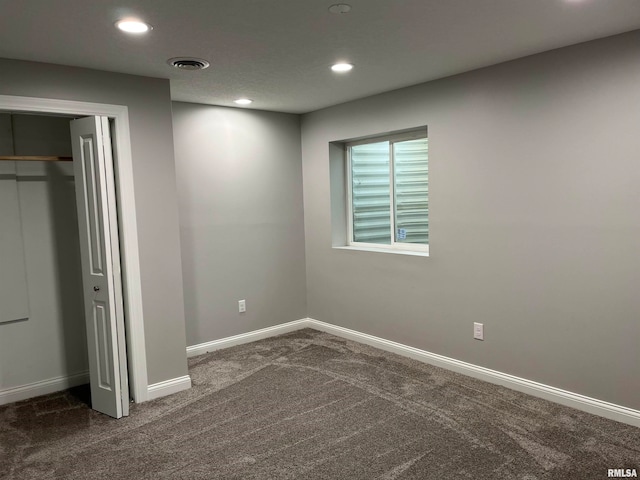 unfurnished bedroom with dark colored carpet and a closet