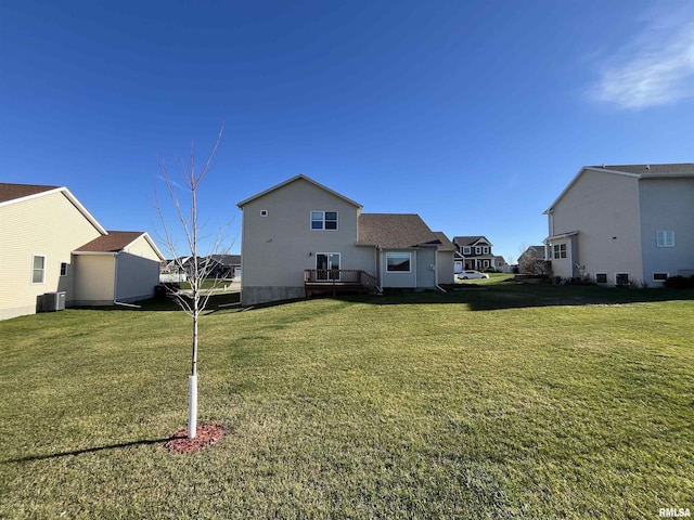 rear view of house featuring central AC unit and a lawn