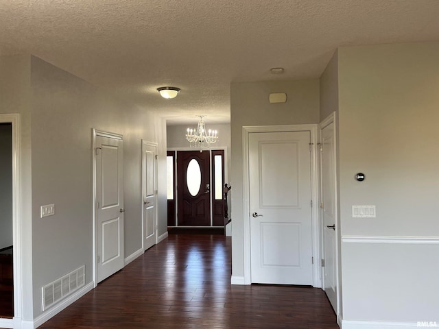 entrance foyer with dark hardwood / wood-style floors, a textured ceiling, and an inviting chandelier