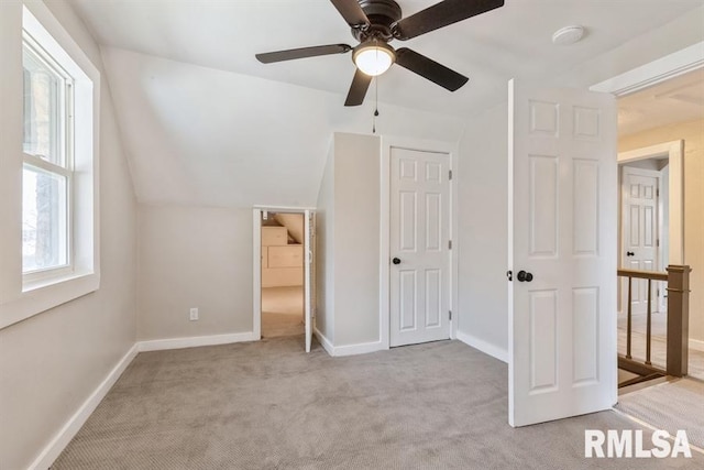 unfurnished bedroom with ceiling fan, a closet, light carpet, and vaulted ceiling