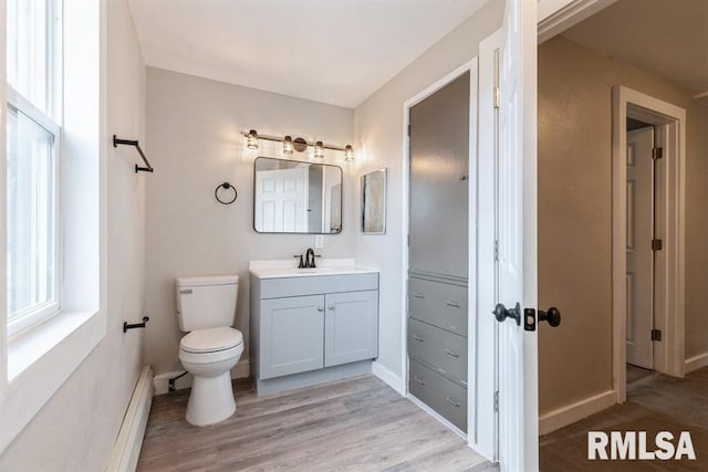 bathroom featuring hardwood / wood-style floors, vanity, toilet, and baseboard heating