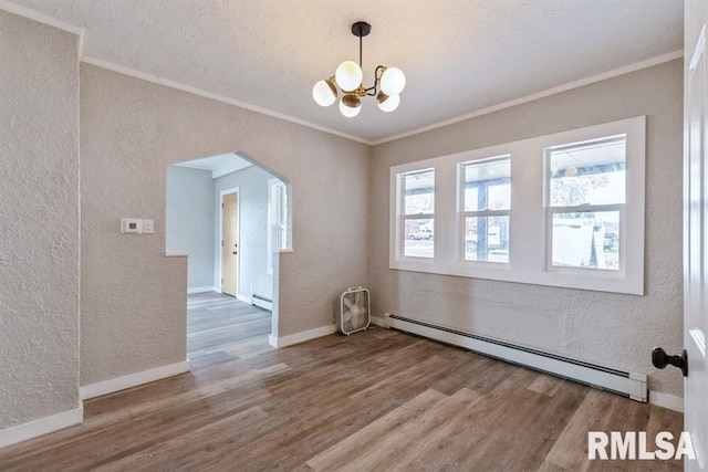 empty room with baseboard heating, ornamental molding, wood-type flooring, and a notable chandelier