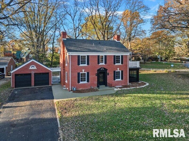 view of front of property with a garage, brick siding, an outdoor structure, a chimney, and a front yard