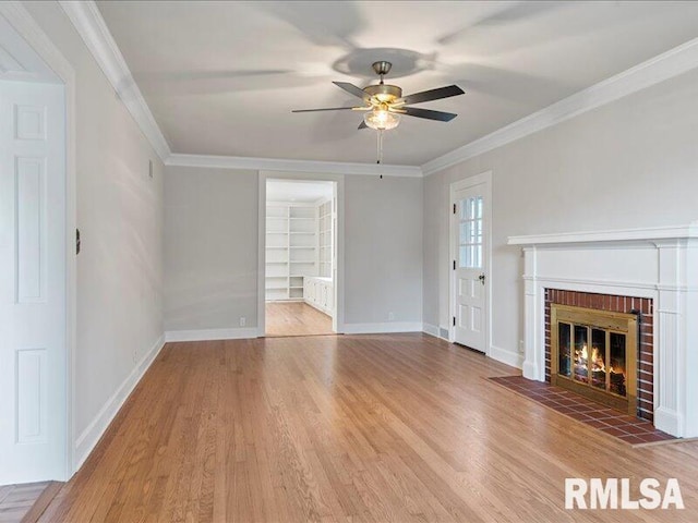 unfurnished living room featuring a fireplace, wood-type flooring, ceiling fan, and crown molding