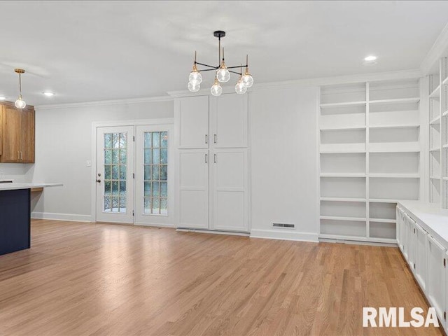 unfurnished dining area with built in shelves, light hardwood / wood-style floors, ornamental molding, and an inviting chandelier