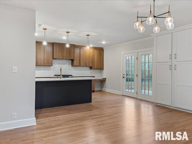 kitchen featuring a breakfast bar, light hardwood / wood-style floors, crown molding, and hanging light fixtures