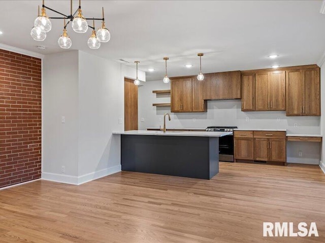 kitchen with sink, brick wall, stainless steel range oven, kitchen peninsula, and pendant lighting