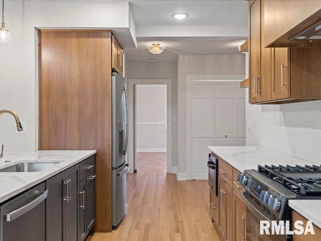 kitchen featuring appliances with stainless steel finishes, premium range hood, light stone counters, and sink