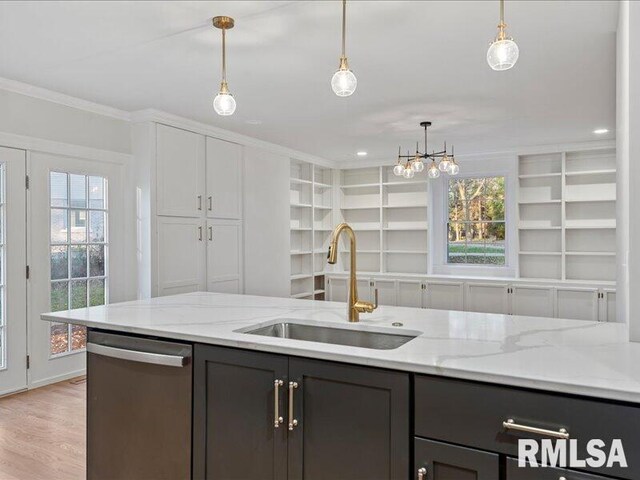 kitchen featuring light stone counters, decorative light fixtures, a sink, and stainless steel dishwasher