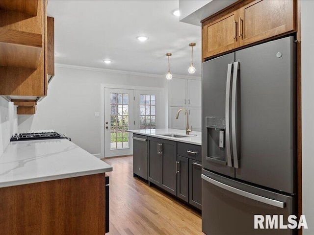 kitchen featuring open shelves, stainless steel appliances, ornamental molding, a sink, and light stone countertops