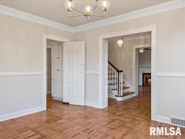 unfurnished room with a notable chandelier, ornamental molding, a fireplace, and light parquet flooring