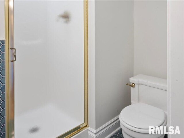 bathroom featuring a stall shower, toilet, and baseboards