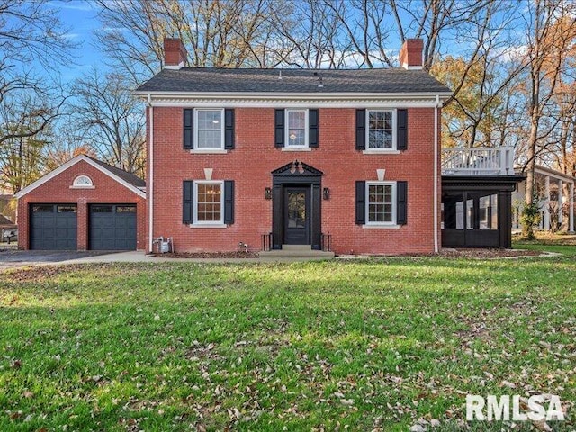 colonial house featuring a garage, an outdoor structure, and a front yard