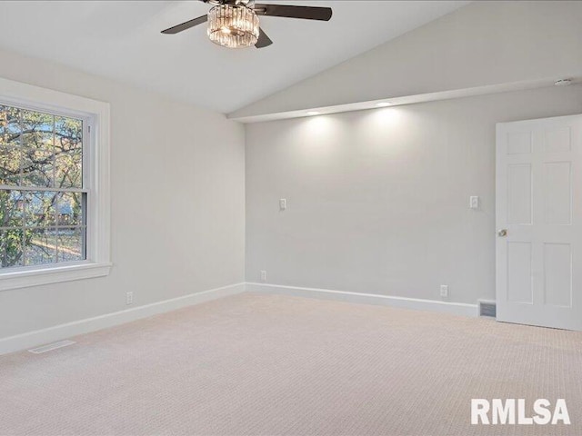 carpeted spare room featuring vaulted ceiling, ceiling fan, and a healthy amount of sunlight