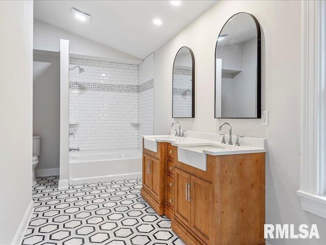 full bathroom featuring tiled shower / bath combo, tile patterned floors, lofted ceiling, toilet, and vanity