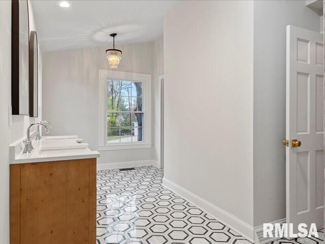 bathroom featuring double vanity, baseboards, tile patterned floors, a chandelier, and a sink