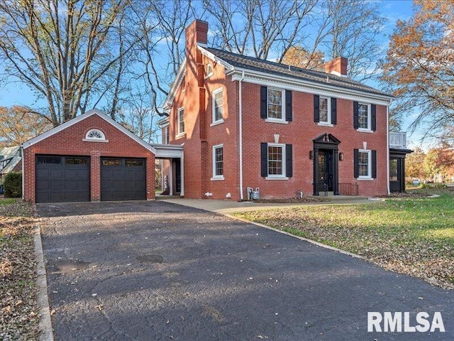 colonial-style house with a front lawn, an outdoor structure, and a garage