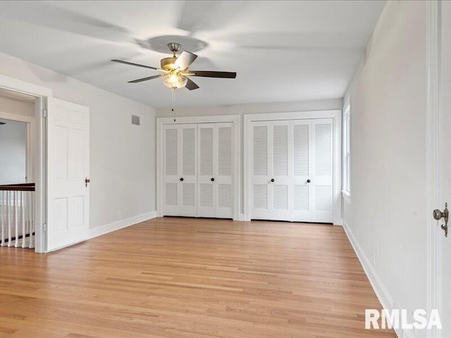 unfurnished bedroom featuring light wood-type flooring, two closets, and ceiling fan